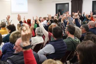 Photo d'un conseil de quartier, avec certains participants levant le doigt.
